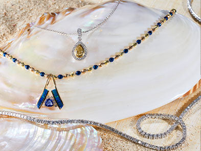 Necklaces sitting on shells and sand