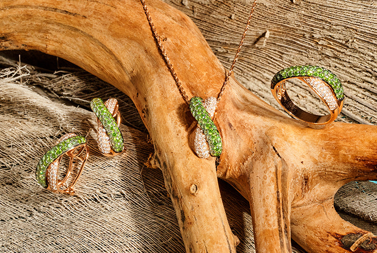 Green diamond rings and necklaces sitting on driftwood