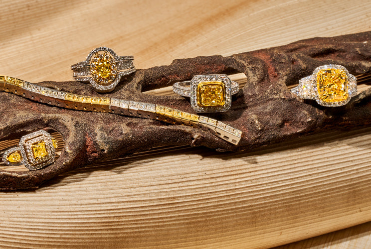 Yellow diamond rings and necklaces sitting on driftwood