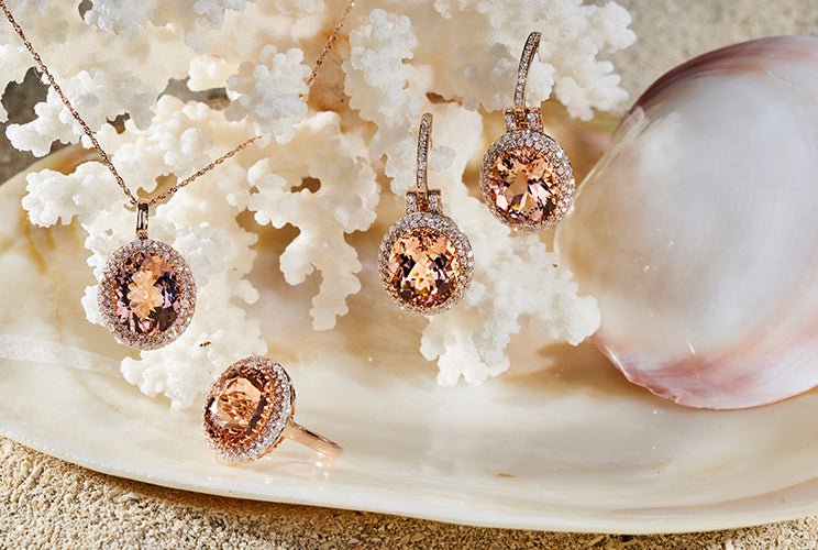 Morganite earrings, necklaces, and rings sitting on coral and shells