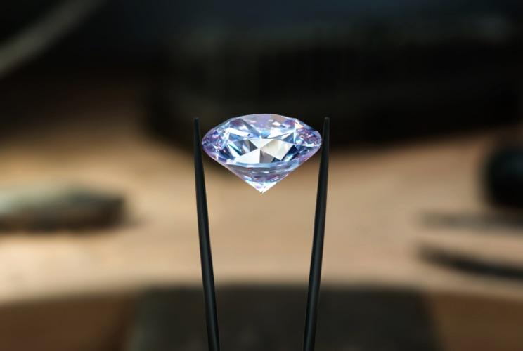 Large diamond being held by a tweezer