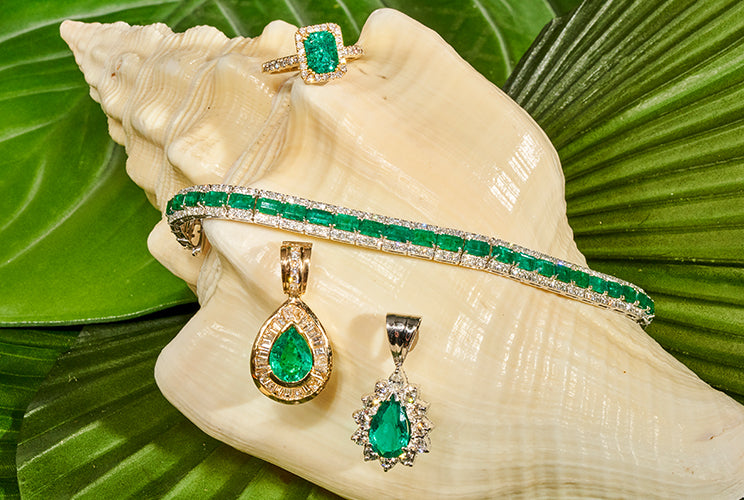Emerald rings, earrings, and necklaces sitting on a conch shell